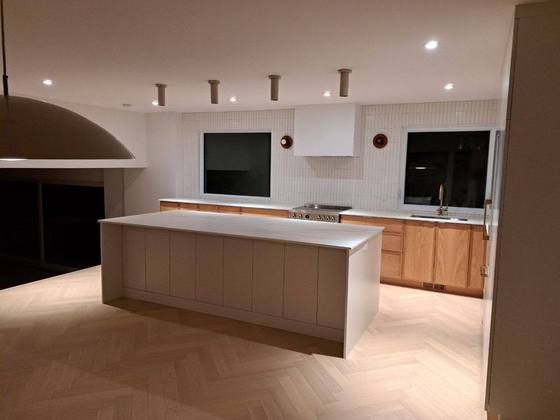 Grande cuisine ouverte avec îlot blanc et plancher à chevrons