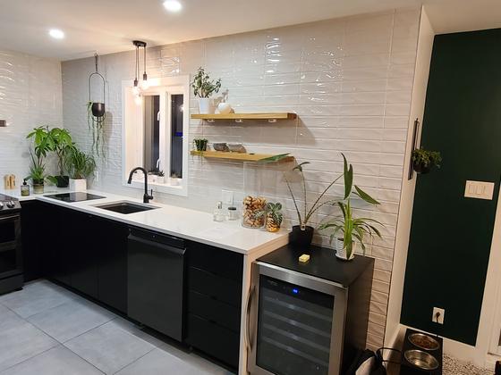 Cuisine noire avec céramique blanche lustrée, tablettes de bois et mur vert